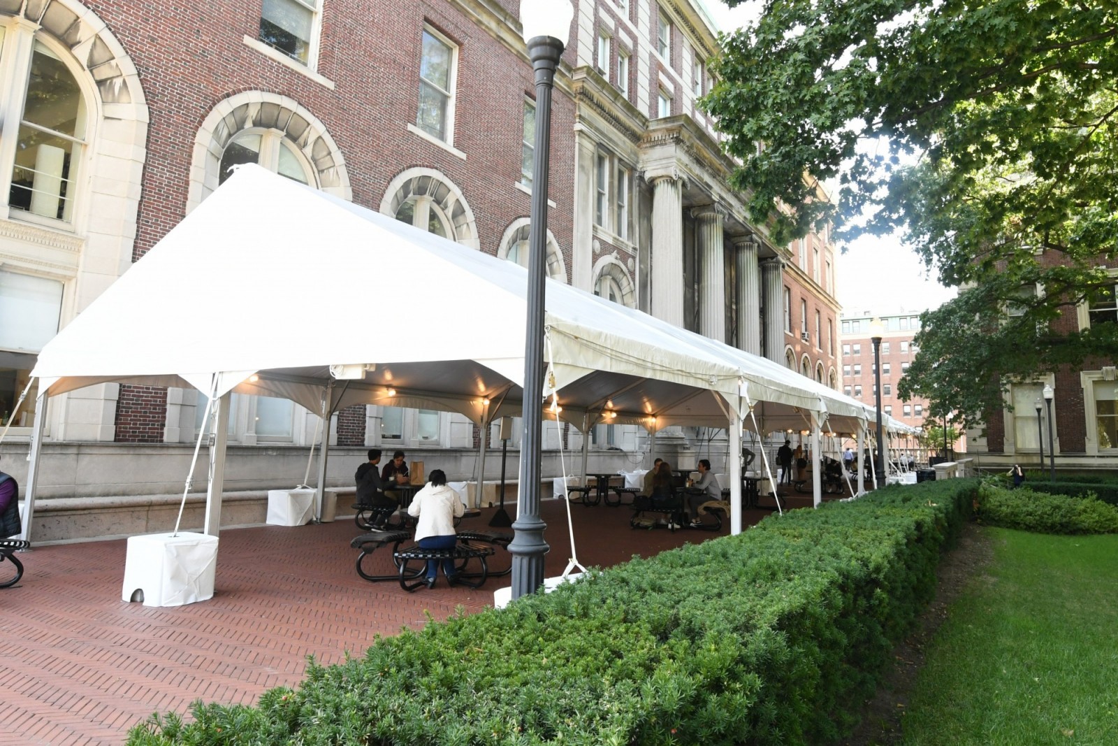 A large, white tent outside of Dodge Hall that has students sitting underneath it.