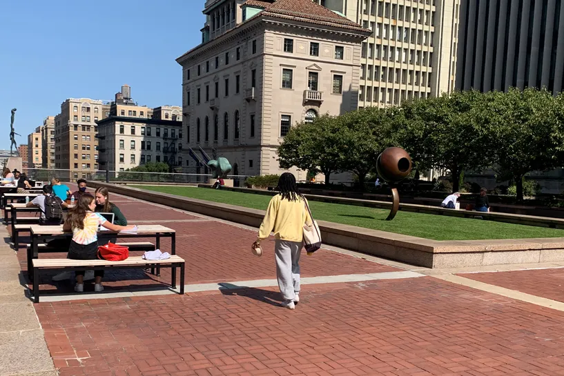 Students sit at benches alongside Revson Plaza.